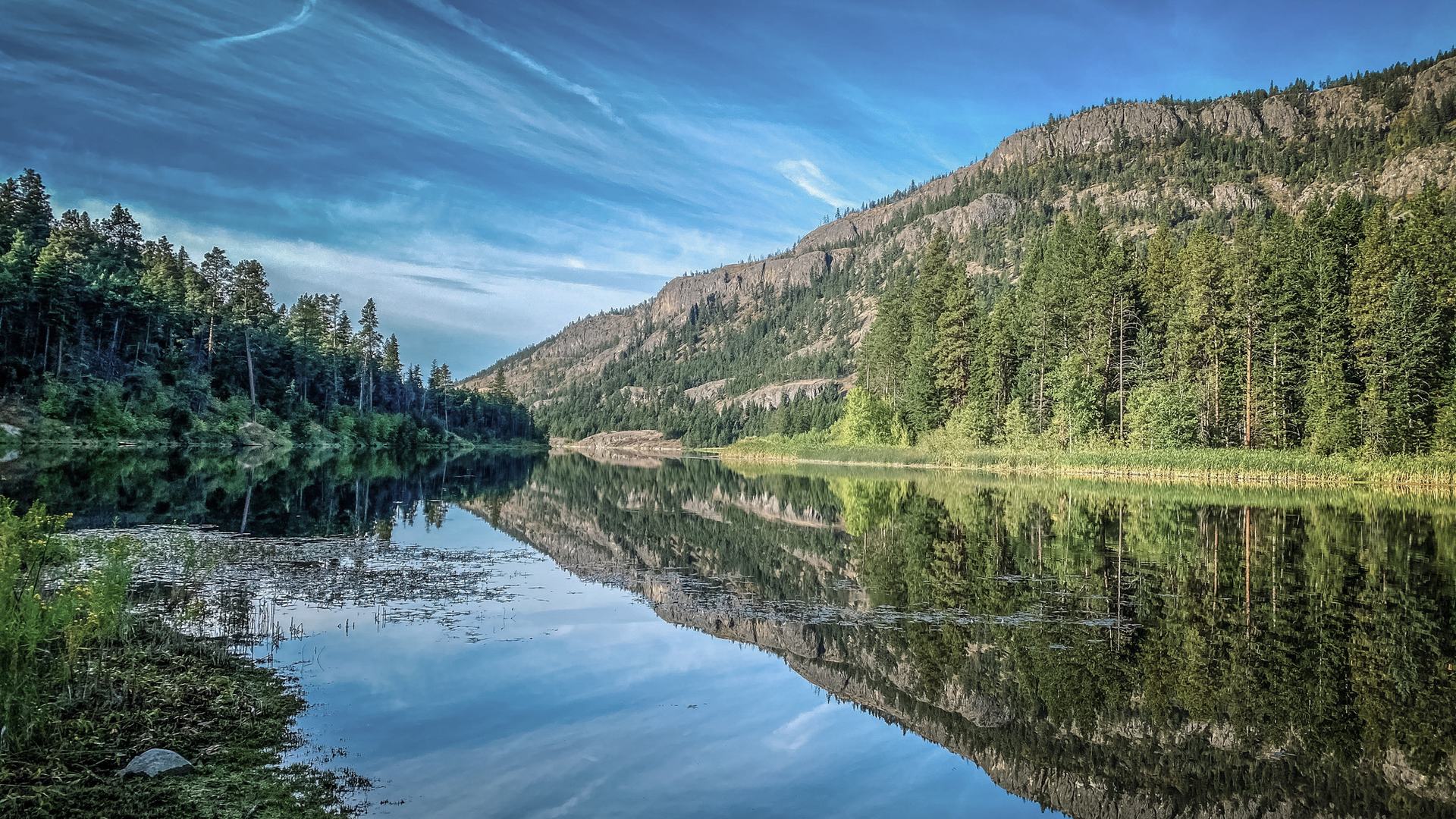 Calm lake reflecting mountains under soft light