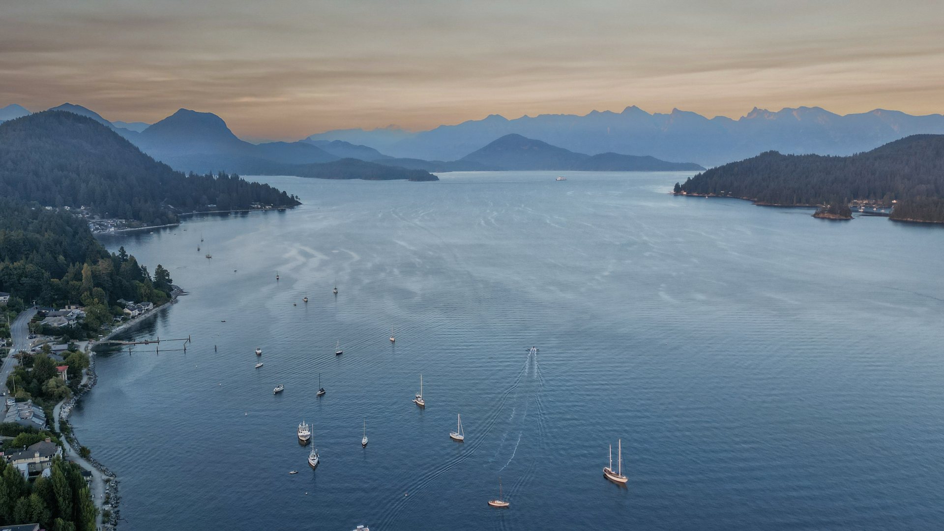 Aerial view of sailboats on a quiet Okanagan lake with distant mountains